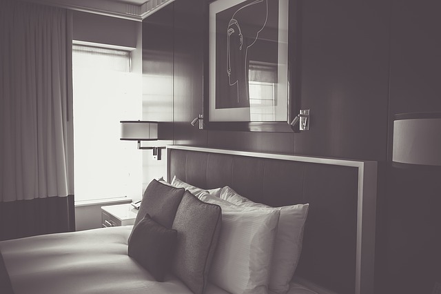 Izba s posteľou s čelom, bielou plachtou a vankúšmi.jpg